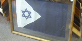 Framed flag suspended between two sheets of glass.